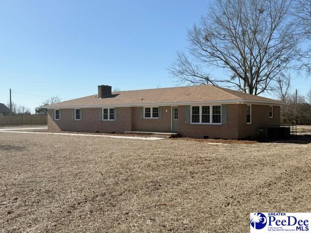 rear view of property with central air condition unit, crawl space, a chimney, and brick siding