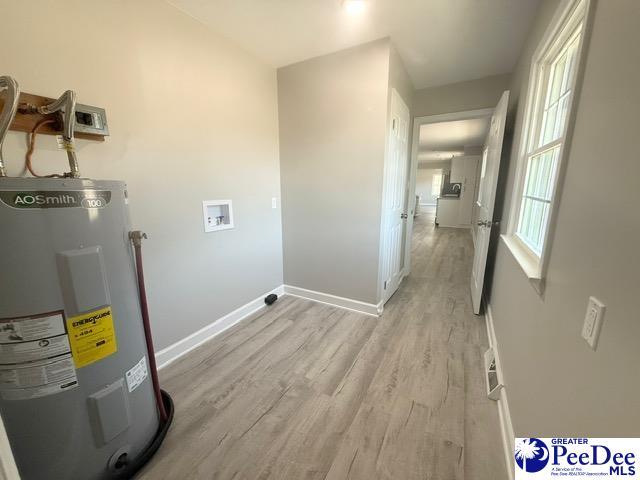 laundry room with hookup for a washing machine, light wood-style flooring, electric water heater, laundry area, and baseboards