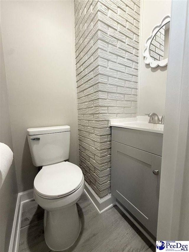 half bath with wood finished floors, vanity, toilet, and baseboards