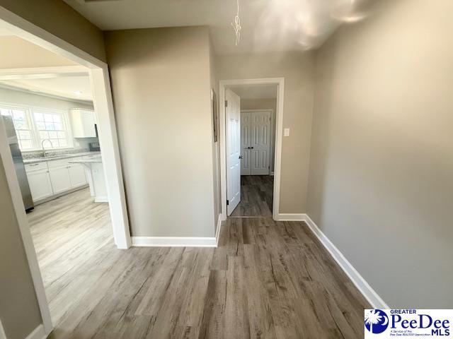 hallway featuring light wood-style floors, a sink, and baseboards