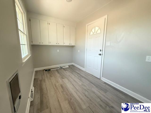 laundry area with wood finished floors, visible vents, and baseboards