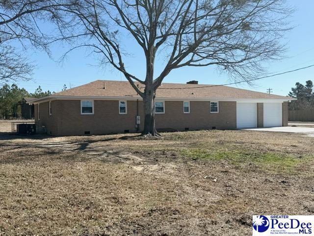 rear view of property featuring a garage, crawl space, brick siding, and concrete driveway