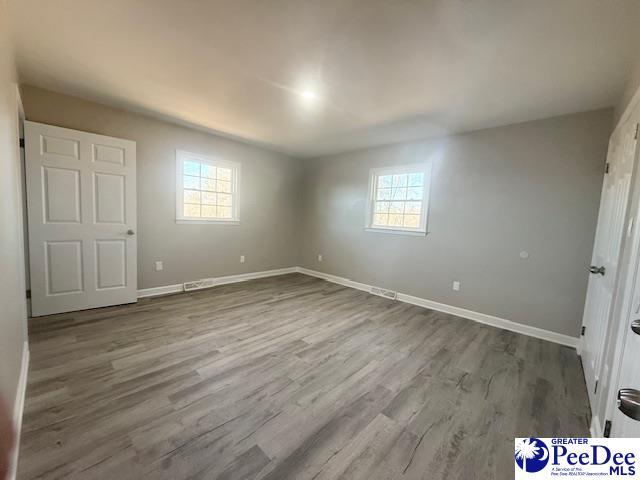 unfurnished bedroom featuring multiple windows, baseboards, and wood finished floors