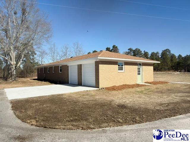 view of property exterior with an attached garage, concrete driveway, and brick siding