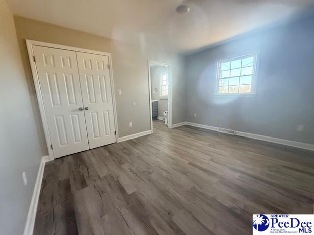 unfurnished bedroom featuring a closet, dark wood finished floors, and baseboards