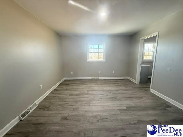 unfurnished room with dark wood-style floors, visible vents, and baseboards