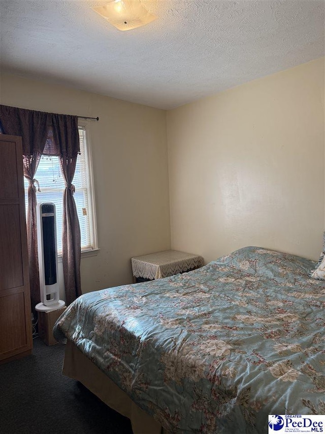 bedroom featuring a textured ceiling and carpet flooring