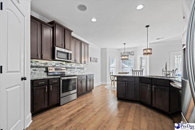 kitchen featuring sink, dark brown cabinets, hanging light fixtures, appliances with stainless steel finishes, and light stone countertops