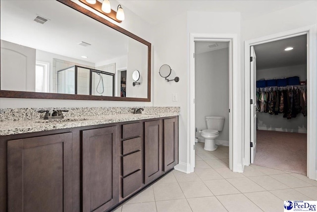 bathroom featuring vanity, toilet, a shower with shower door, and tile patterned flooring