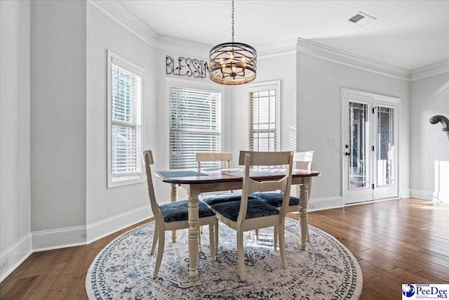 dining area featuring crown molding, dark hardwood / wood-style floors, and a notable chandelier