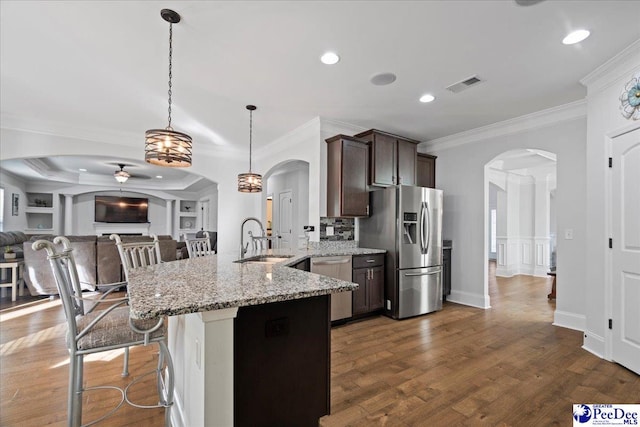 kitchen featuring sink, hanging light fixtures, light stone counters, dark brown cabinetry, and stainless steel appliances