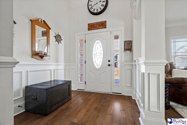 foyer featuring ornamental molding, dark hardwood / wood-style floors, and ornate columns