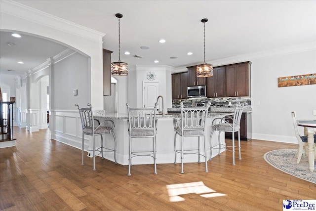 kitchen featuring light stone countertops, pendant lighting, backsplash, and dark brown cabinetry