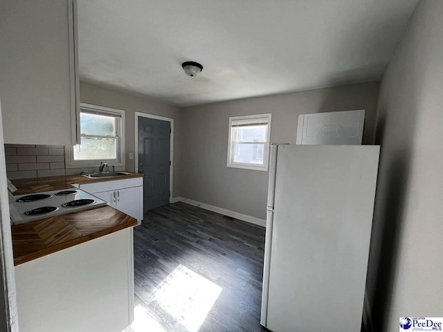 kitchen with butcher block countertops, sink, white cabinets, white fridge, and cooktop