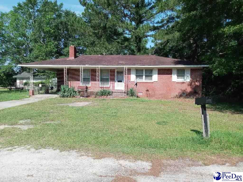 single story home with a front lawn, a carport, and a porch