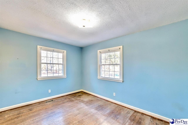 spare room with hardwood / wood-style floors and a textured ceiling