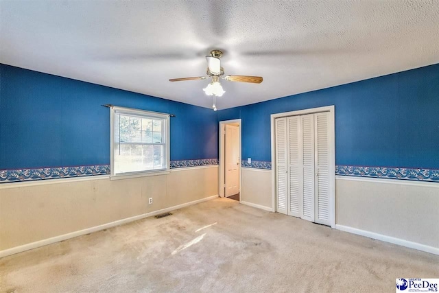 unfurnished bedroom with ceiling fan, carpet floors, a closet, and a textured ceiling