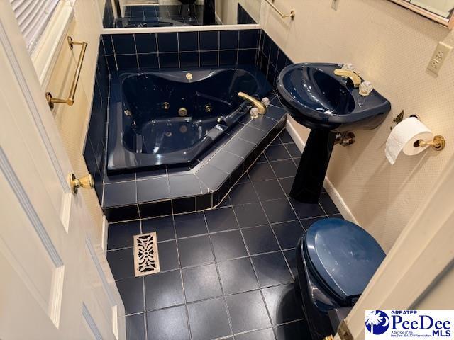 bathroom featuring tiled tub, tile patterned flooring, and toilet