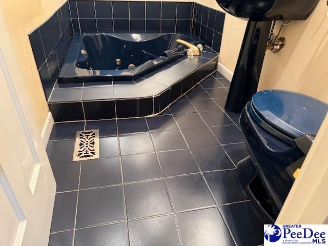 bathroom featuring toilet, tile patterned flooring, and tiled tub