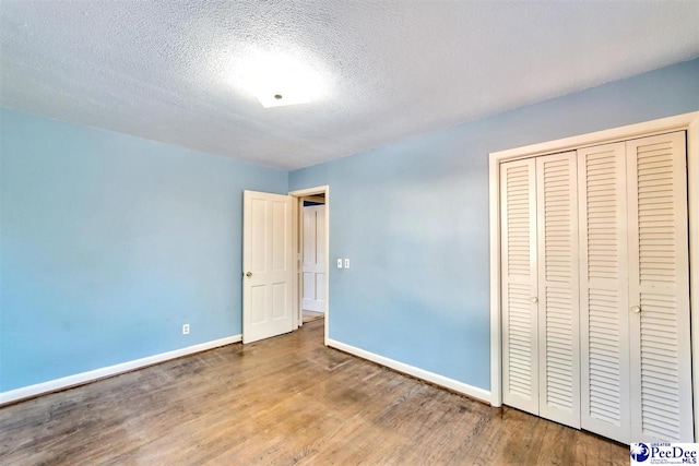 unfurnished bedroom featuring wood-type flooring, a closet, and a textured ceiling