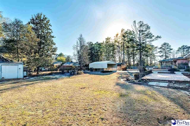 view of yard featuring a shed, a wooden deck, and a carport