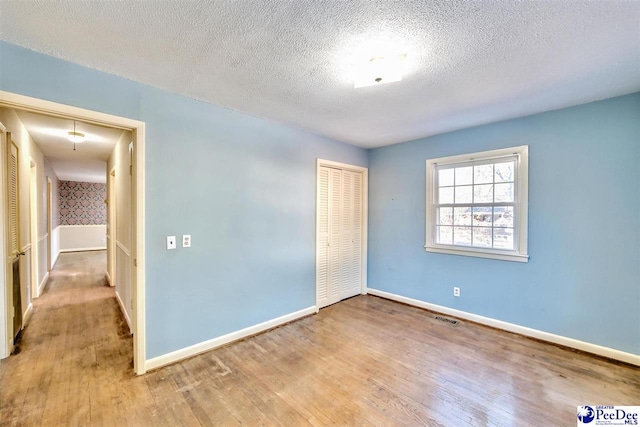 spare room featuring light hardwood / wood-style floors and a textured ceiling