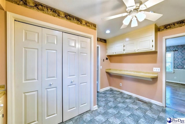 kitchen with ceiling fan, built in desk, and white cabinets