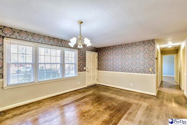 spare room featuring hardwood / wood-style floors, a notable chandelier, and a textured ceiling