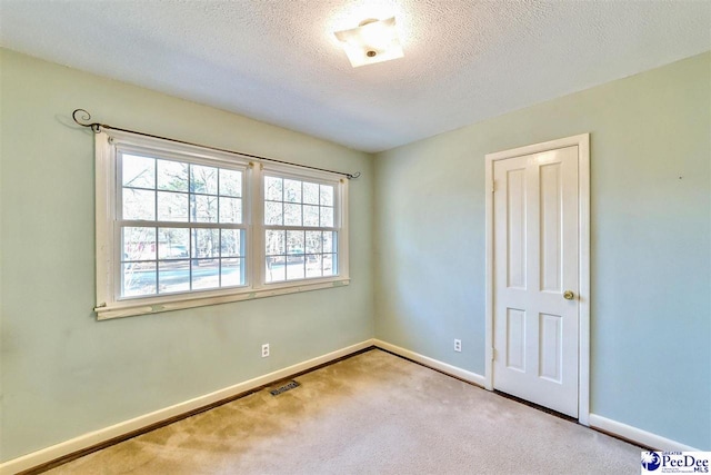 unfurnished room with light carpet and a textured ceiling