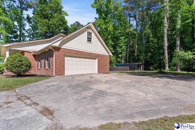 view of home's exterior with concrete driveway, brick siding, fence, and a garage