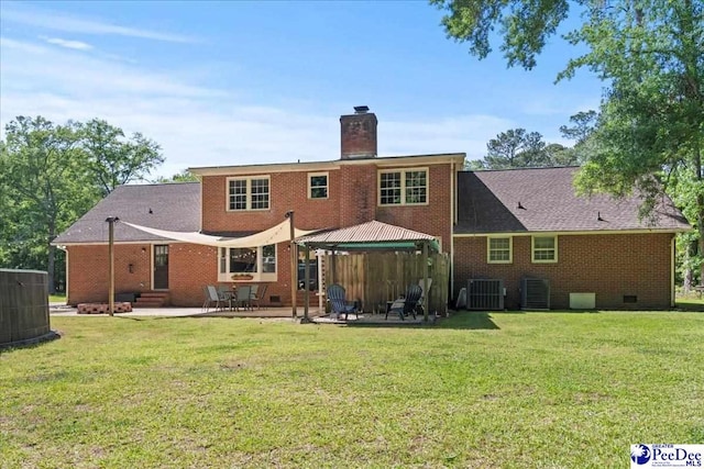 rear view of house featuring a gazebo, a chimney, brick siding, and central AC