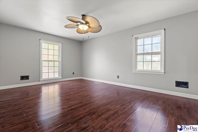 unfurnished room featuring a ceiling fan, baseboards, dark wood-style floors, and plenty of natural light