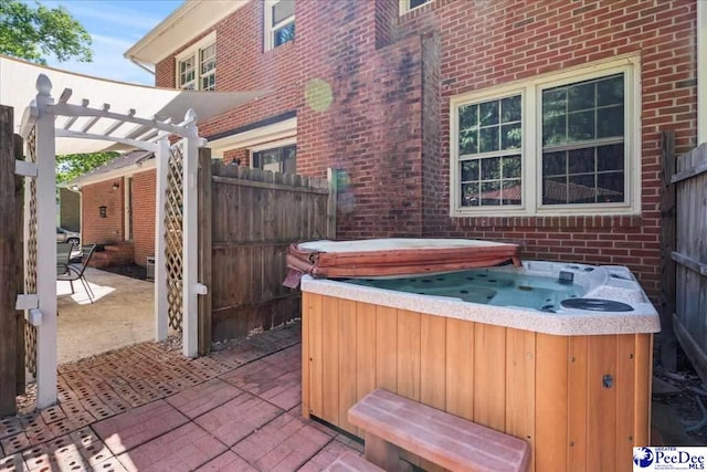view of patio featuring a hot tub, a pergola, and fence