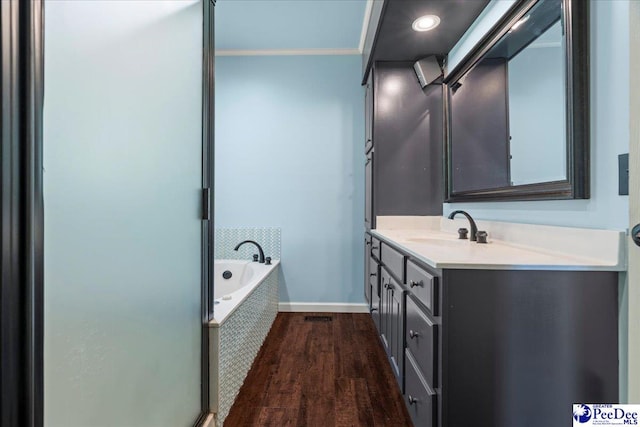 full bath featuring baseboards, a bath, vanity, crown molding, and wood finished floors