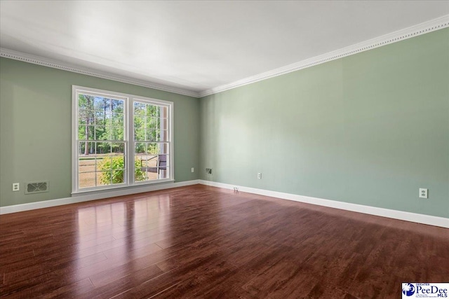 spare room featuring baseboards, dark wood-style flooring, ornamental molding, and visible vents