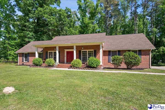 single story home with a porch, brick siding, and a front yard