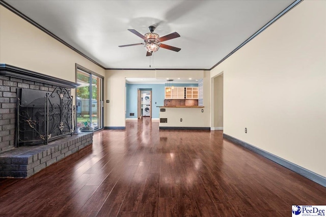 unfurnished living room with wood finished floors, stacked washer / drying machine, a fireplace, crown molding, and ceiling fan