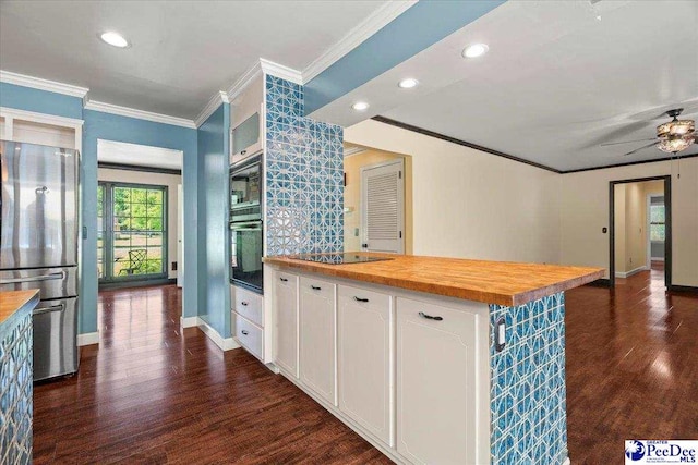 kitchen featuring wood counters, black appliances, dark wood-type flooring, crown molding, and white cabinetry