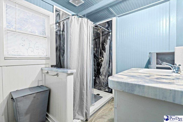 bathroom with sink, wooden walls, and walk in shower