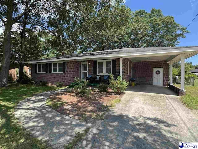 1124 N 4th Ave, Dillon, SC 29536 - ranch-style house featuring brick siding, concrete driveway, a carport, and a porch