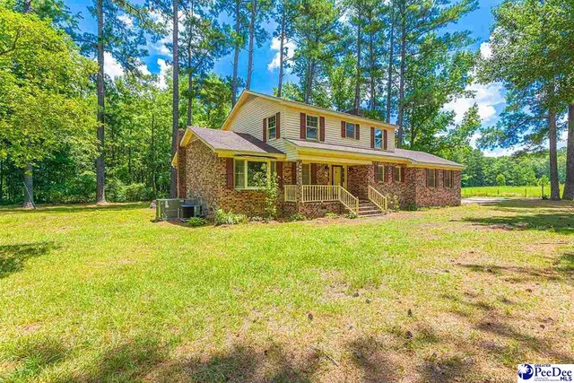 view of front of property featuring a front yard, central AC unit, and covered porch