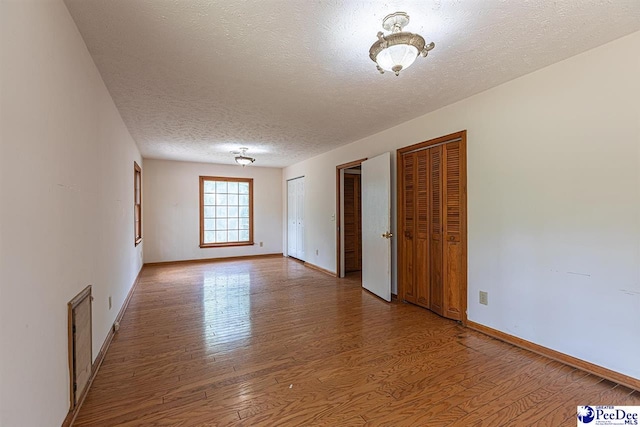 spare room featuring hardwood / wood-style floors and a textured ceiling