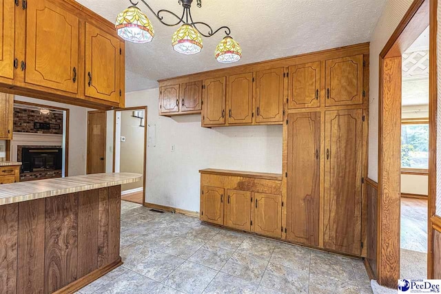 kitchen featuring a fireplace, decorative light fixtures, and a textured ceiling