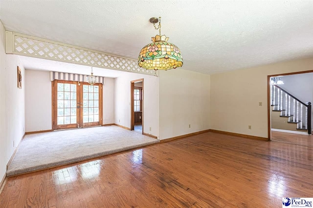 empty room featuring wood-type flooring, a textured ceiling, and french doors