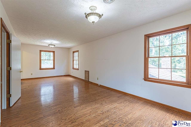 spare room featuring light hardwood / wood-style flooring and a textured ceiling