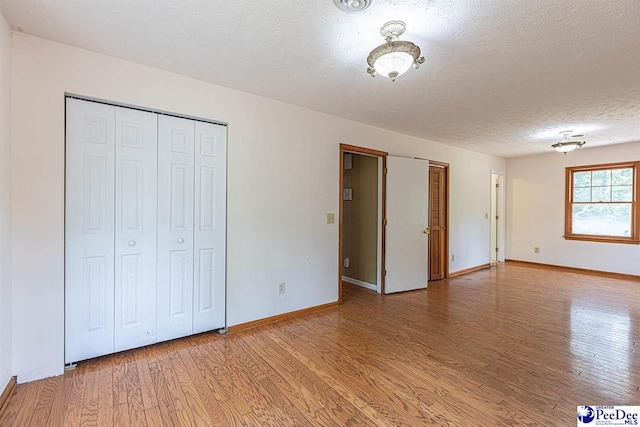 unfurnished bedroom featuring a closet, light hardwood / wood-style floors, and a textured ceiling