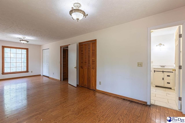 spare room with hardwood / wood-style flooring, sink, and a textured ceiling