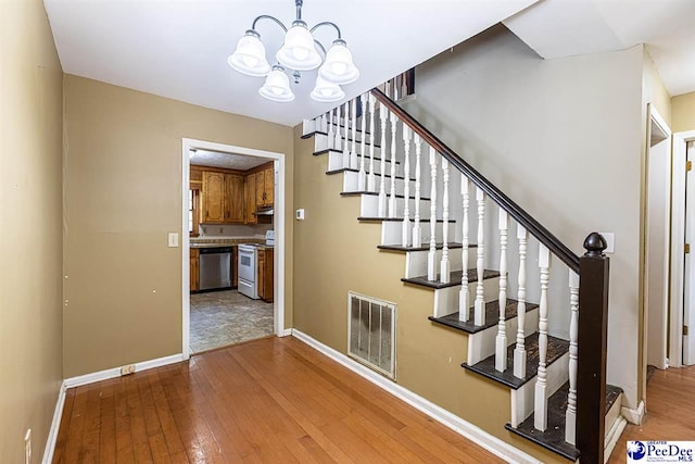 stairs featuring hardwood / wood-style flooring and an inviting chandelier