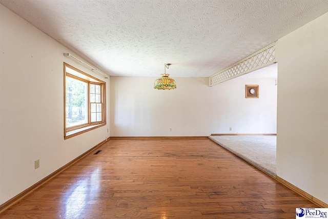 empty room with wood-type flooring and a textured ceiling