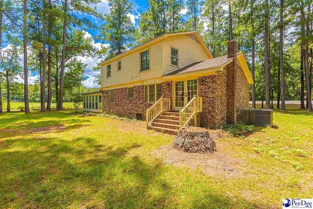 rear view of property featuring a yard and central AC